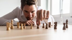 Young man uses chess pieces to visualize and strategize his next negotiation